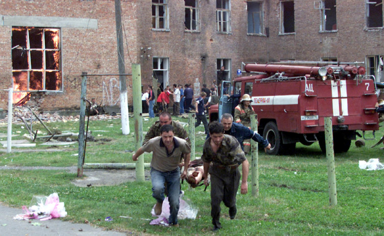 Volunteers carry an injured civilian to safety in the town of Beslan