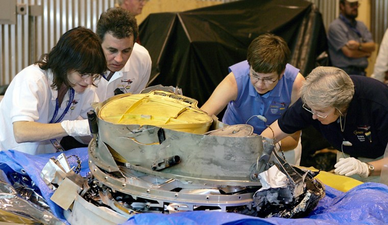 Jet Propulsion Lab's Amy Jurewicz and Don Sevilla, and Johnson Space Center's Judy Allton and Eileen Stansbery, left to right, examine and pick pieces of dirt from the Genesis capsule after it crashed Wednesday in Dugway Proving Ground, Utah. 