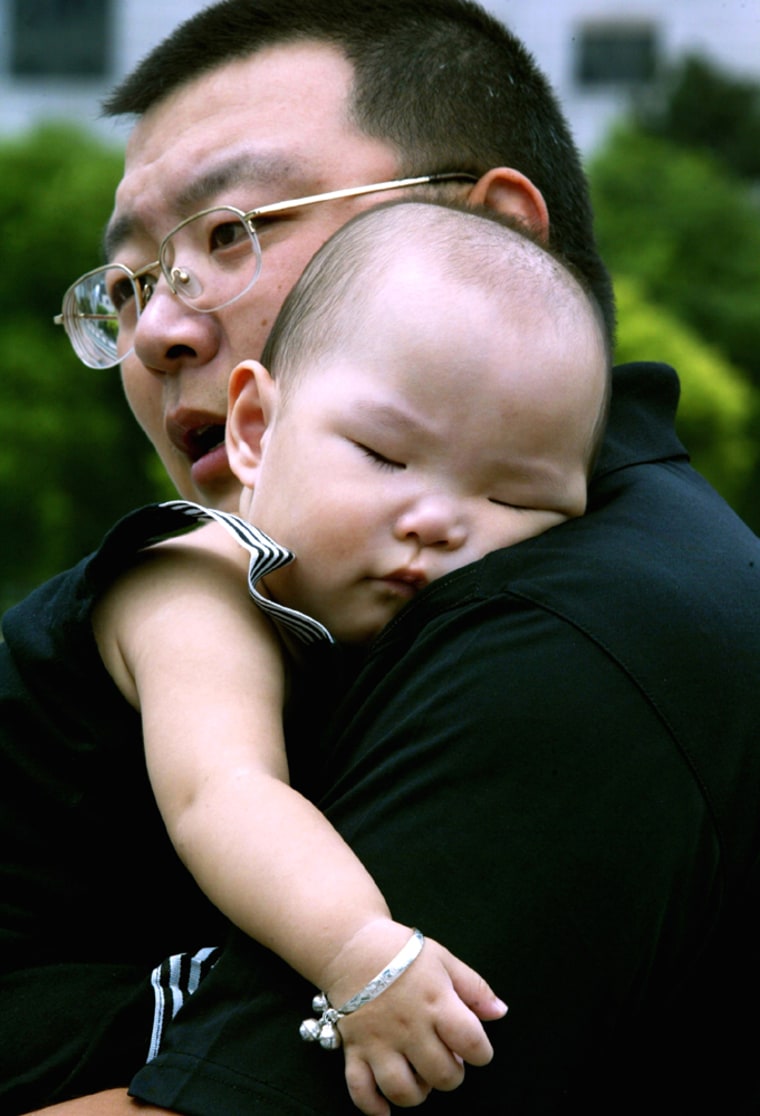 A Chinese father carries his sleeping child at a park in Shanghai