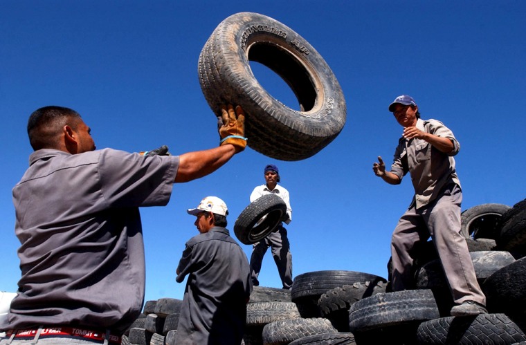 Workers pile used tires at Ciudad Juarez's collection center, where some of the estimated 5 million tires will be converted to electricity.