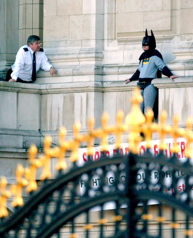A fathers' rights campaigner dressed as Batman protests on a balcony at Buckingham Palace in London