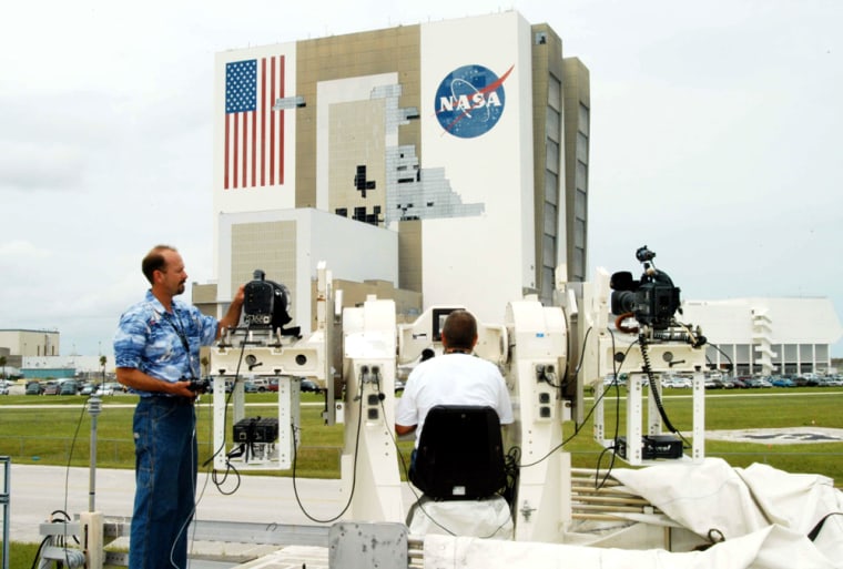 Kennedy Space Center videographer Glenn Benson adjusts a high-definition camera being used to photograph the south wall of NASA's Vehicle Assembly Building, which sustained damage from Hurricane Frances as it passed over central Florida during the Labor Day weekend.