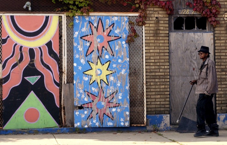 A man walks past an abandoned building adorned with a mural in the Mt. Pleasant area of Cleveland on Sept 15.