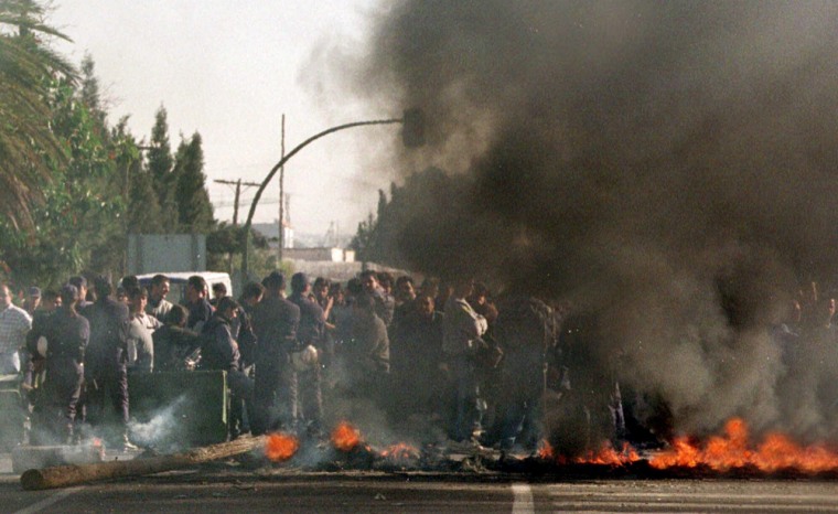 Police watch as residents of El Ejido make burning tire barricade to block the highway to this city in southern Spain, Monday Feb. 7, 2000 during the third day of anti-immigrant violence sparked by the stabbing death of Spanish woman. (AP Photo/J.M.Vidal/EFE)
