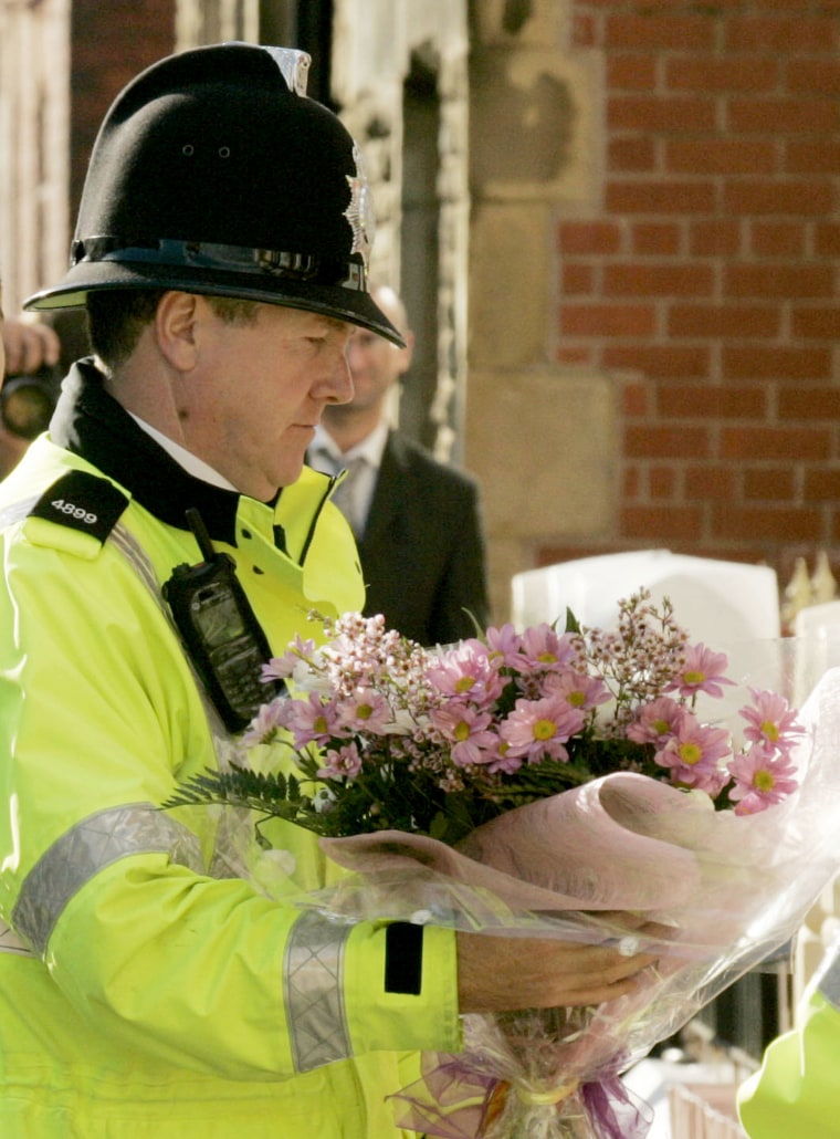 A police officer carries flowers to the home of the mother of British Iraq hostage Kenneth Bigley in Liverpool