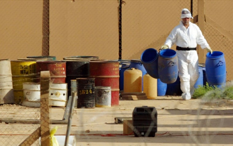 File photograph shows  U.N. nuclear expert carrying barrels at the Tuwaitha storage site near Baghdad