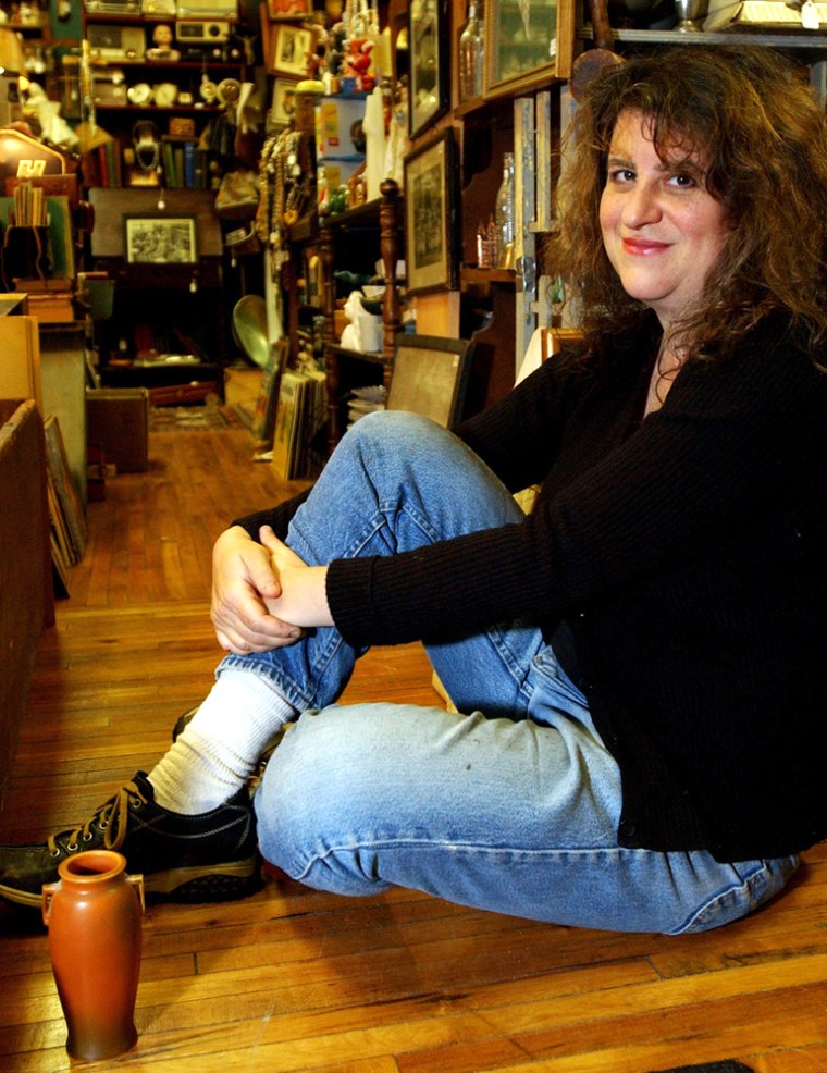 Laura Levine poses on Thursday, Sept. 30, 2004, in her shop, Homer and Langley's Mystery Spot,  in Phoenicia, N.Y., with a vase, lower left, that she says contains about one teaspoon of the ashes of actress Veronica Lake, the \"it-girl\" of the 1940s and who died a pauper in New York City in 1973. (AP Photo/Jim McKnight)