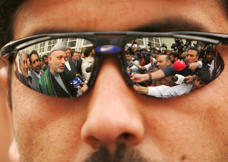 Afghan President Karzai is seen reflected in the sunglasses of a security guard in Kabul