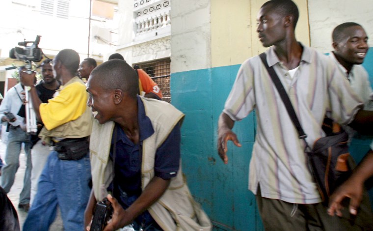 Haitian journalists react after hearing gunfire from one of the main entrance to the pro-Aristide slum of Bel-Air, in Port-au-Prince, Haiti Friday, Oct.15, 2004.(AP Photo/Ariana Cubillos)