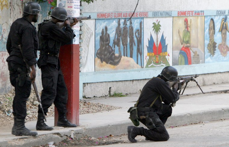 Haitian Police take position and shoot from a street close to an entrance to the pro-Aristide slum of Bel-Air, in Port-au-Prince, Haiti, on Friday.