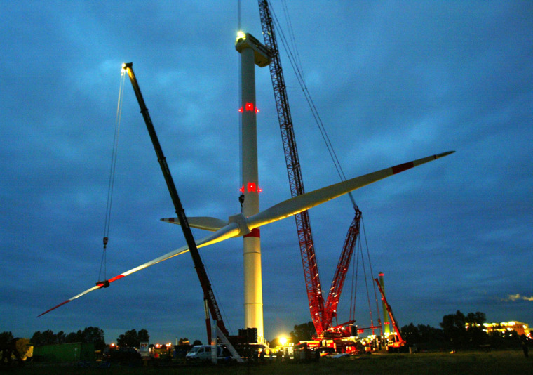 Cranes lift up the rotor of a giant wind generator near Hamburg