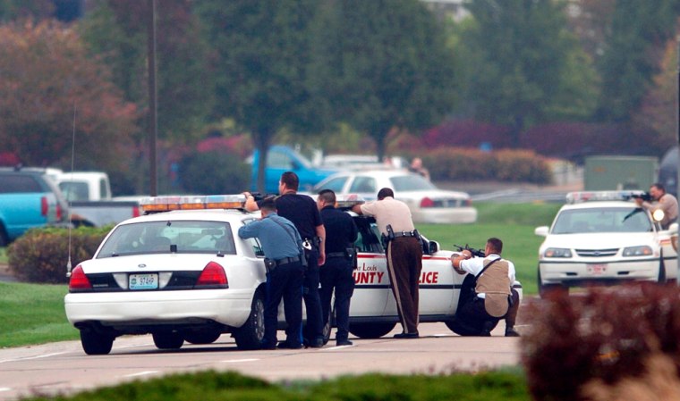 Law enforcement officers watch the Beltservices Corp. plant in Earth City, Mo. on Thursday, after a former employee entered the business with a gun and opened fire.