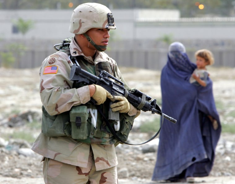 Afghan woman begs as US soldier from ISAF patrols in Kabul