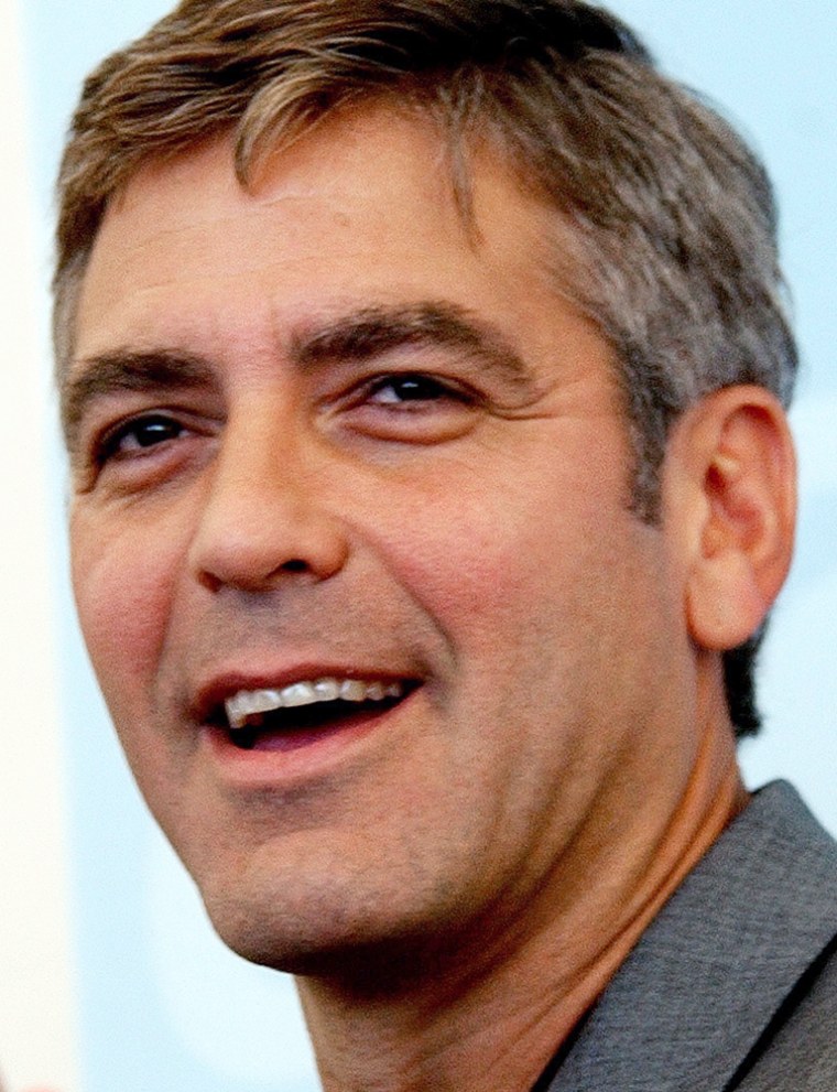** FILE ** U.S. actor George Clooney gestures during a photo call at the 60th Venice Film Festival in Venice, Italy, in this Sept. 3, 2003 file photo. Clooney shoots baskets with the local kids, carries grandmothers' groceries uphill and works hard on pronouncing \"buon giorno.\" He has international stardom and rascally good looks, but in Laglio, Italy where Clooney owns an 18th century mansion with a private dock on Lake Como, the star is simply \"bravo\" - Italian for \"a good person.\" (AP Photo/Luca Bruno, File)