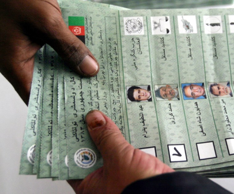 Afghan election worker hands a pile of counted ballot papers to a colleague in Kabul