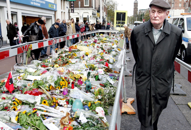 A man passes by a flower memorial to slain Dutch filmmaker Theo Van Gogh at the scene of his murder, Amsterdam, Friday, Nov. 5, 2004. Van Gogh was murdered Tuesday on the Amsterdam street. An alleged Islamic extremist has been arrested in connection with the murder  (AP Photo/ Guus Dubbelman)