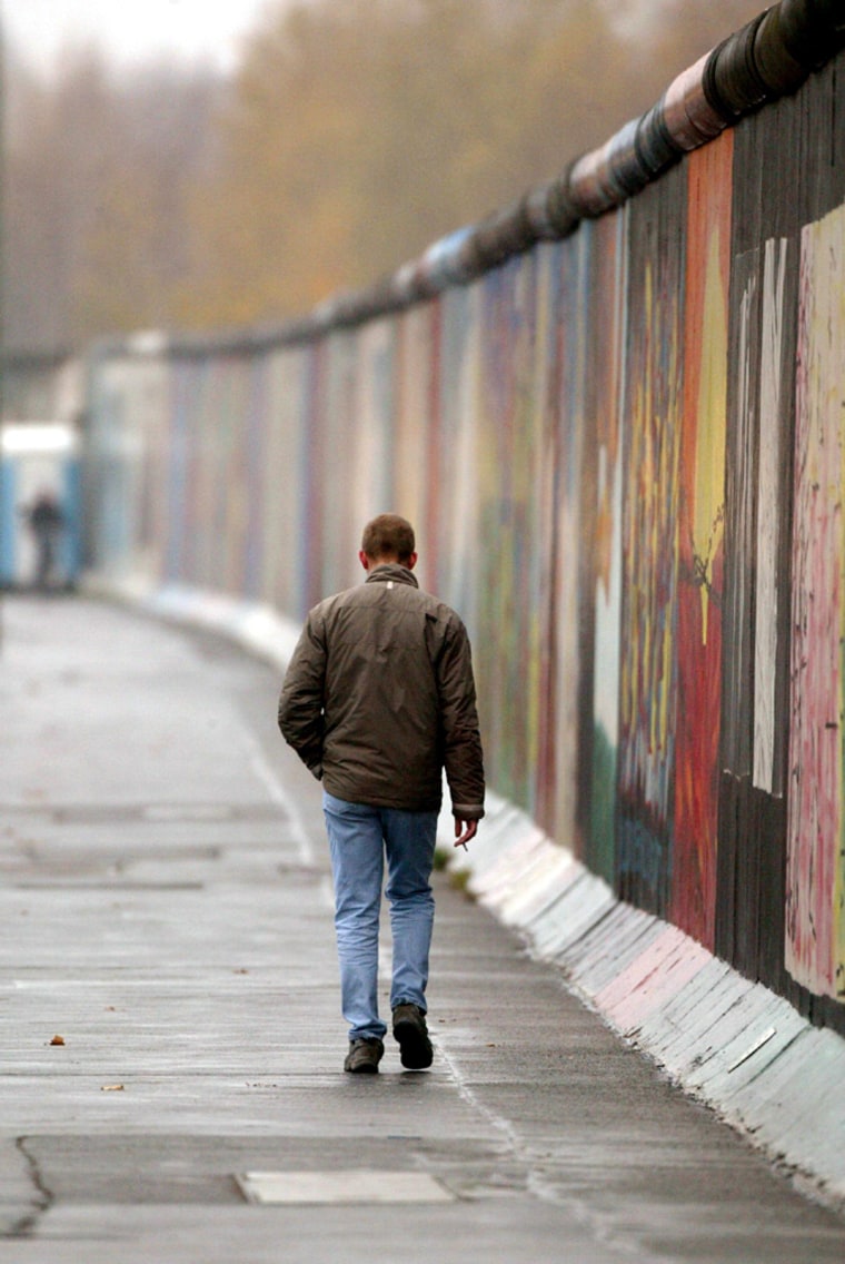 An unidentified man walks past remains of the Berlin Wall