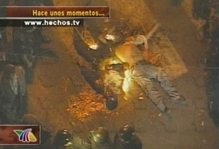 In this image from television the bodies of two officers lie at the scene after a crowd of people angry about recent kidnappings at a local school cornered the federal agents taking photos of students leaving the building and burned the officers alive Tuesday Nov. 23, 2004 in Mexico City's southeastern outskirts. The latest example of mob justice in a country beset by corrupt police and high crimes rates. (AP Photo/TV AZTECA via APTN) ** TV OUT **
