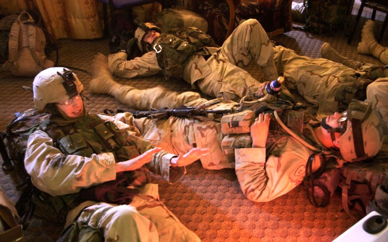 U.S. Army 1st Battalion, 24th Infantry soldiers relax near a space heater after a traditional Thanksgiving dinner of turkey and ham was delivered to their outpost in Mosul, Iraq Thursday, Nov. 25, 2004. Insurgents rose up this month in Mosul, Iraq's third-largest city, during an offensive by U.S. and Iraqi forces in Fallujah. (AP Photo/Jim MacMillan)