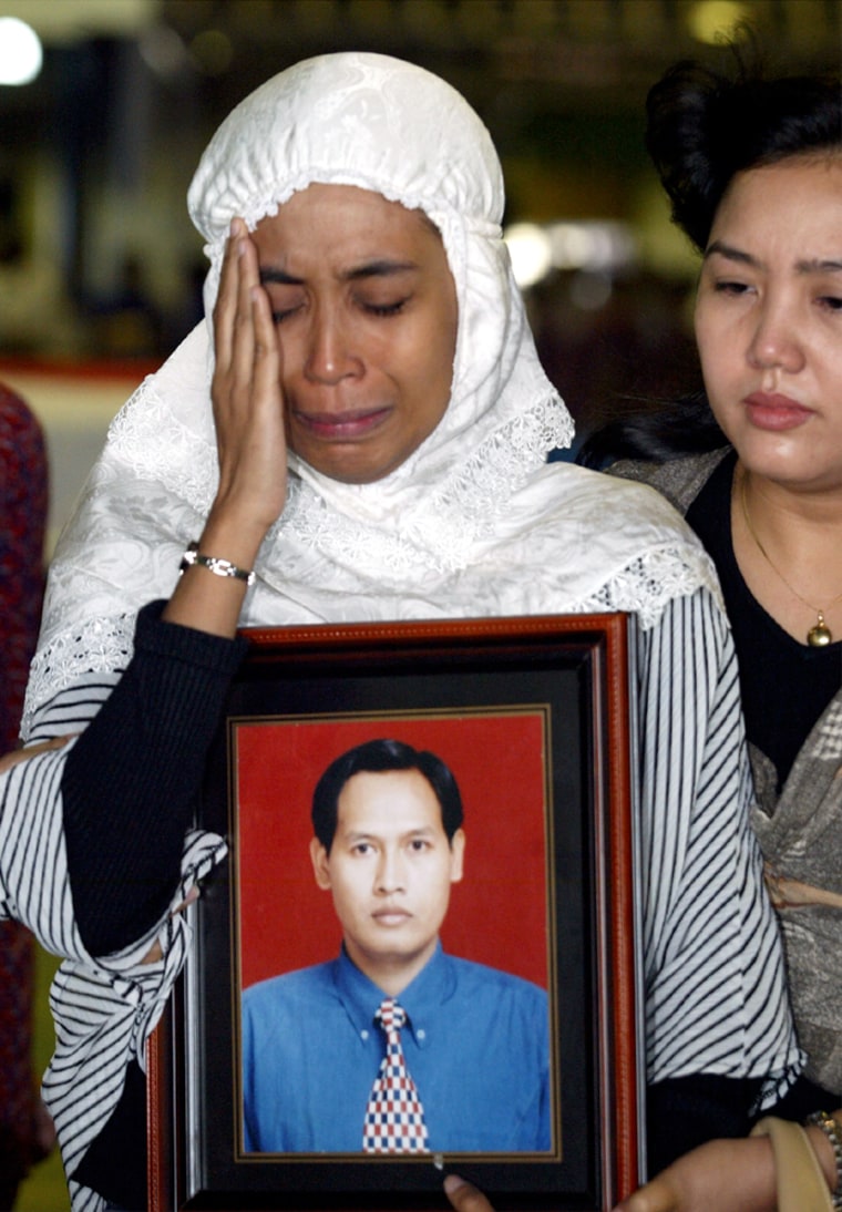 Wife of Indonesian pilot of plane that skidded off runway carries portrait in Jakarta