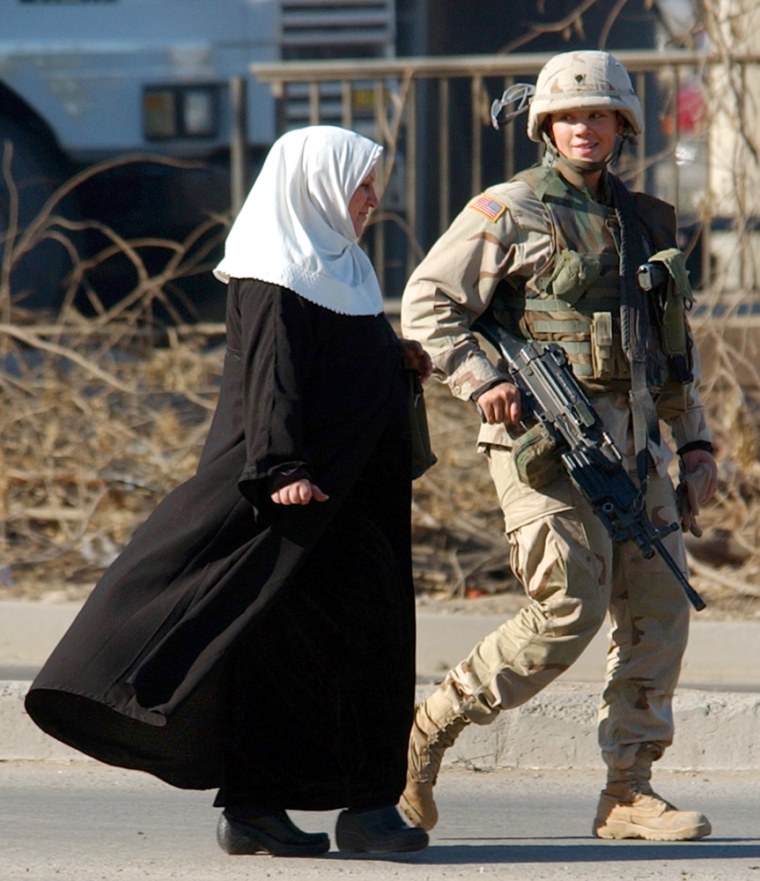 A female U.S. soldier escorts a woman out of the danger zone following a suicide car bombing in Baghdad on Nov. 29.
