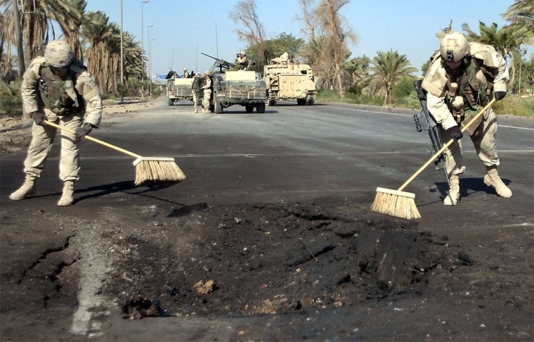 U.S. Army soldiers repair asphalt damaged by a suicide bomber along a perilous stretch of highway connecting Baghdad's airport with the Green Zone.