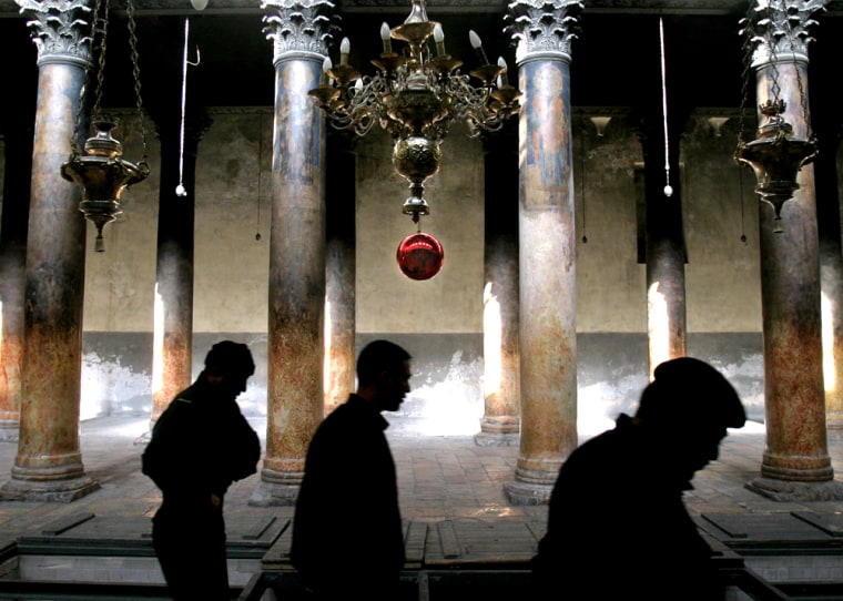 A Christmas ornament hangs from a chandelier as Palestinian police officers walk in the Church of the Nativity, the site traditionally believed to be the birthplace of Jesus Christ in the West Bank town of Bethlehem, on Monday.