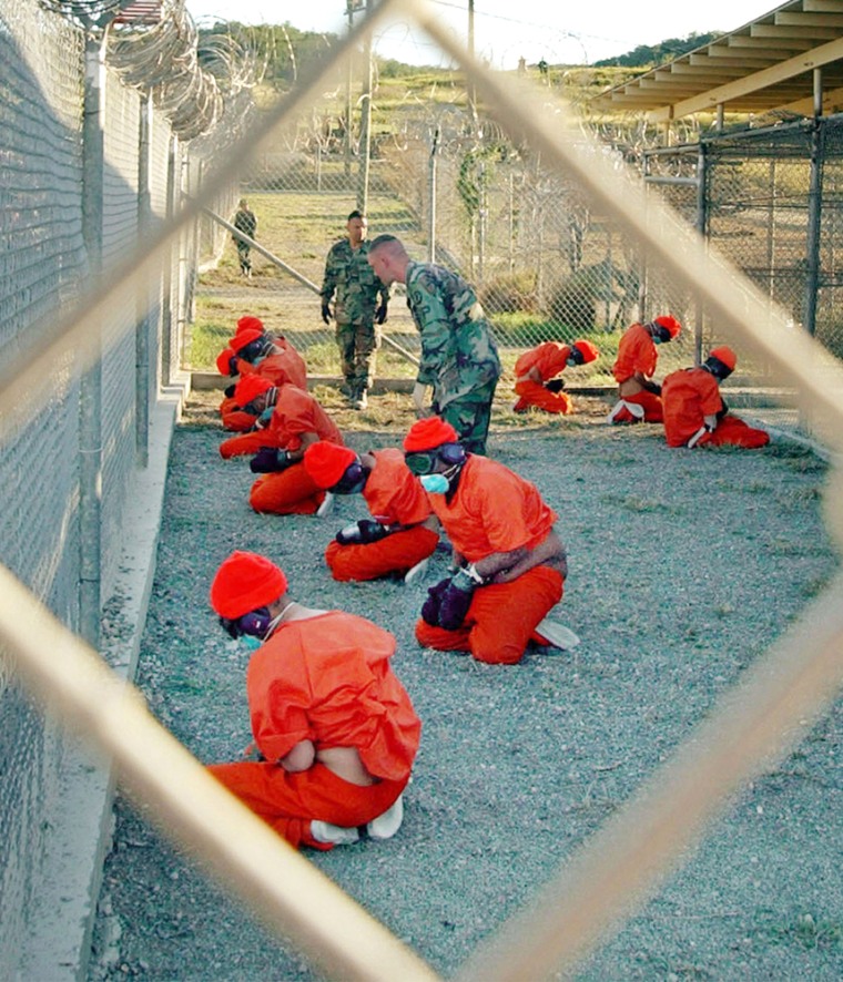 Suspected Taliban and al-Qaida detainees sit in a holding area at Camp X-Ray at Guantanamo Bay, Cuba, in a Jan. 11, 2002, file photo. 