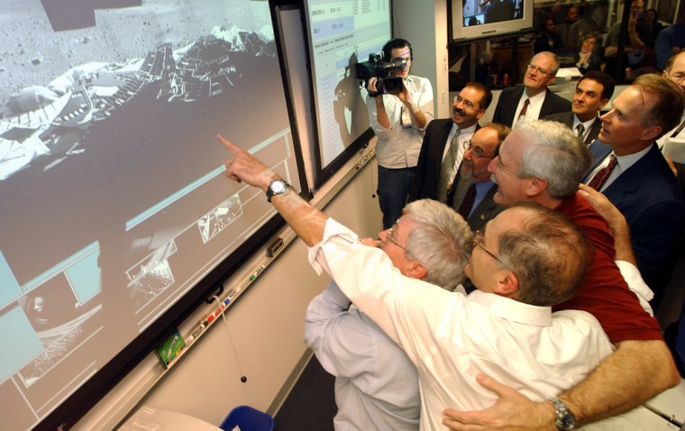NASA Administrator Sean O'Keefe (in red) embraces Charles Elachi, director of the Jet Propulsion Laboratory, as Elachi points at one of the first images from the Spirit rover on Mars on Jan. 3. Spirit could conceivably keep on working for NASA even after O'Keefe leaves the agency in 2005.