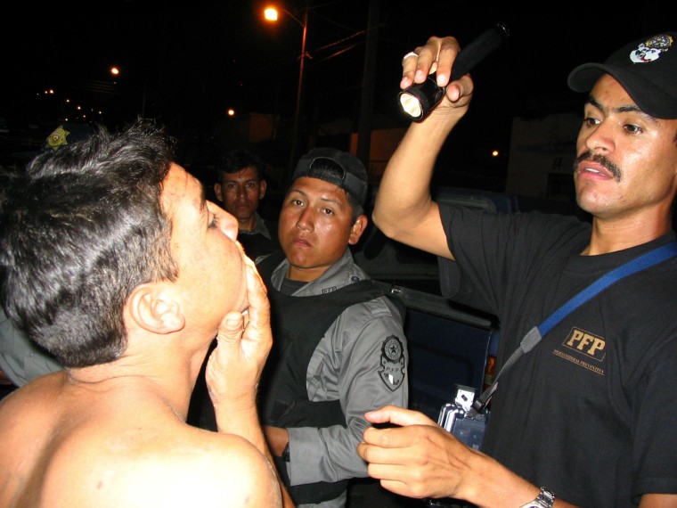 Mexican police search a man's mouth for gang tattoos in Tapachula in December.