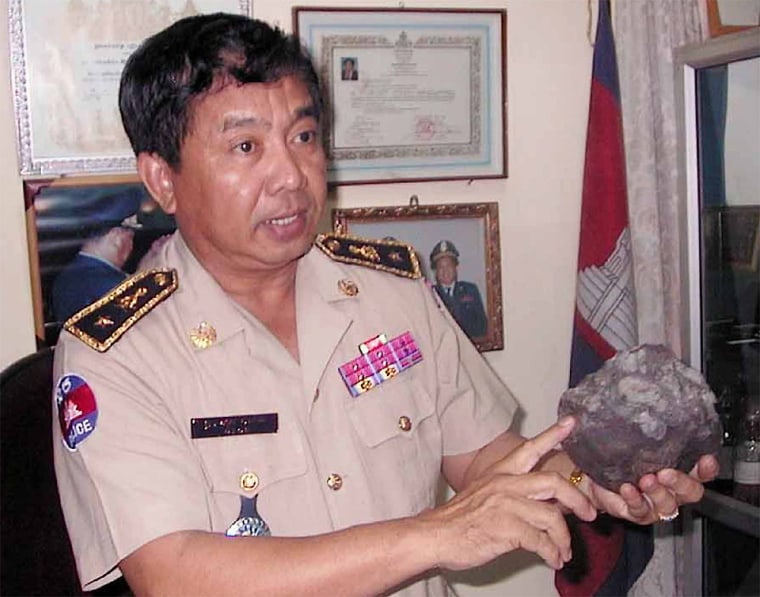 Police chief shows a 10 lb meteorite rock which landed in a former Khmer Rouge zone, northwest Cambodia