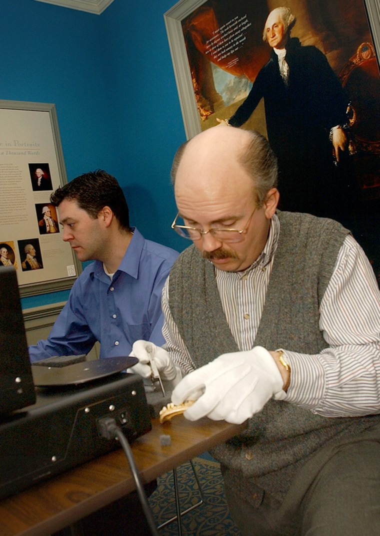 Scott Swank, DDS, Curator of The Dr. Samuel D. Harris National Museum of Dentistry readies a George Washington denture for laser scanning at the museum on Tuesday, Jan. 25, 2005, in Baltimore. In the background is Matt Tocheri a Phd Anthropology student from Arizona St. University who is assisting. Researchers hoping to dispel George Washington's image as a stiff-jawed, boring old man are taking a bite out of history through a high-tech study of his famous false teeth. The researchers were in Baltimoreon Tuesday to perform laser scans on a set of Washington's dentures at the National Museum of Dentistry, dentures, they say, that were not made of wood as commonly believed. (AP Photo/The Baltimore Sun, Jed Kirschbaum)