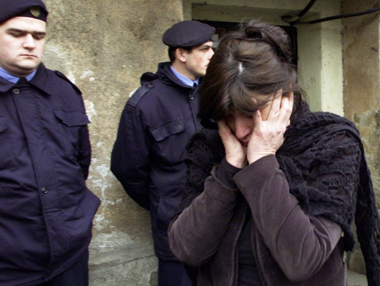 Police officers stand by as an unidentified relative of Georgian Prime Minister Zurab Zhvania cries outside his mother's home in Tbilisi, Thursday, Feb. 3, 2005. Georgian Prime Minister Zurab Zhvania, who helped lead the revolution that toppled the corruption-tainted regime of Eduard Shevardnadze, was killed early Thursday by an apparent natural gas leak, the ex-Soviet republic's interior minister said. (AP Photo/Shakh Aivazov)