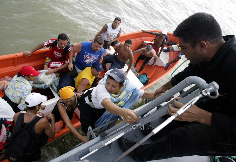 Venezuelans climb aboard a navy ship during an evacuation after torrential rains in Vargas state