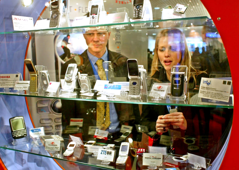 Visitors look at smartphones during the 3GSM World Congress 2005 in Cannes, France on Monday.