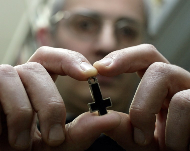 Professor at Romes Regina Apolostolorum pontifical university holds an inverted cross used by Satanic worshippers