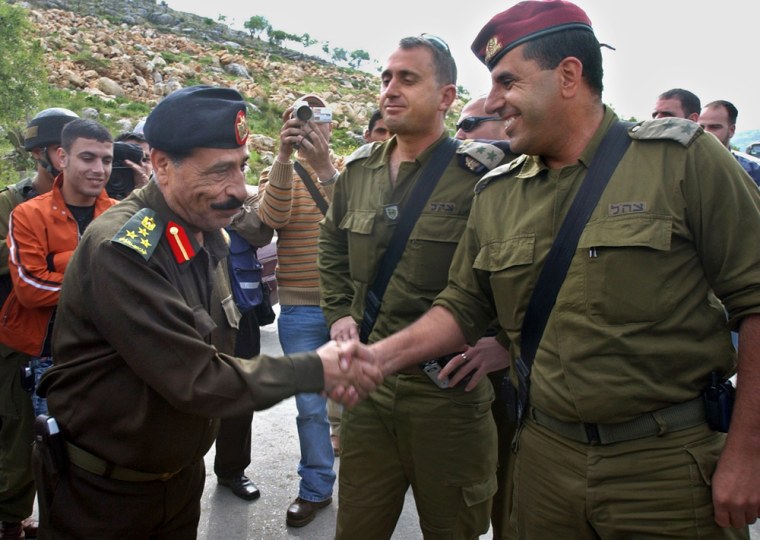Palestinian police officer Said Abu Pasha, left, and Israeli  Lieutenant Colonel Said, right,  solemnify the handover of control of the area with a handshake after the opening of a gate in the outskirts of  the West Bank town of Tulkarem on Tuesday  March 22 2005.  Israel completed its handover of Tulkarem to Palestinian security control Tuesday, ceremonially unlocking a gate that had blocked traffic between the town and main points in the West Bank. At center is the Israeli commander of the Northern West Bank area of  Col. Tamir Hayman.(AP Photo/ Nasser Ishtayeh)