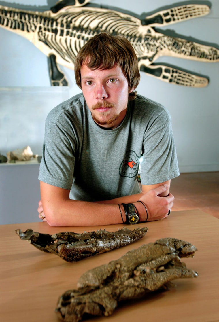 Researcher Lucas Buchanan from Melbourne's Monash University poses in front of the fossilized skull and bones of a new species of pre-historic crocodile