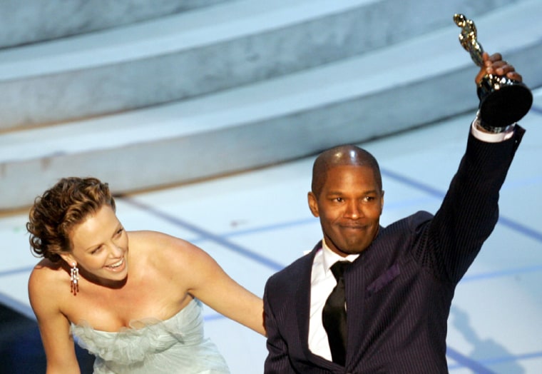 Jamie Foxx accepts his best actor award from actress Charlize Theron at the 77th annual Academy Awards