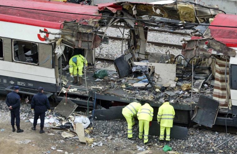 Spanish railway workers and police examine the debris of a destroyed train at Madrid's Atocha railway station on March 12, 2004. A year after terrorists killed 191 people, both U.S. and Spanish officials say that there is no evidence that al-Qaida leadership authorized or even knew of the plan.   