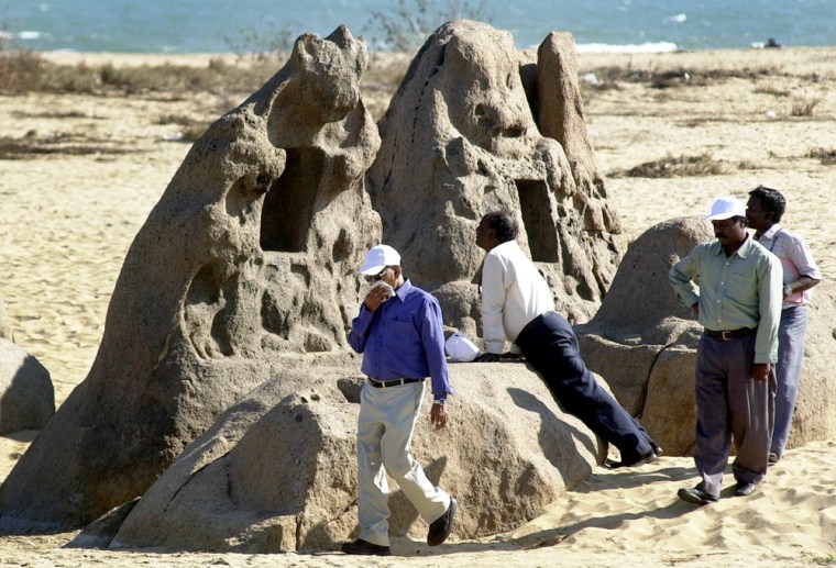 **  FILE ** Officials from the Archeological Survey of India investigate an ancient artifact which was uncovered by the Dec. 26 tsunami near the Shore Temple at Mahabalipuram, 45 miles south of Madras, India, in this Feb. 17, 2005 file photo.The tsunami scrubbed away six feet of sand from a section of beach, uncovering a small cluster of long-buried boulders carved with animals, gods and servant girls. (AP Photo M. Lakshman/File)