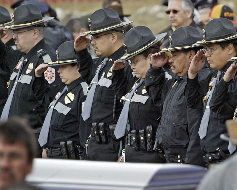 Police officers salute as the casket of slain officer Daryl Lussier is displayed in Red Lake, Minn., on Saturday. Lussier's grandson, 16-year-old Jeff Weise, shot Lussier and eight others before killing himself Monday. 