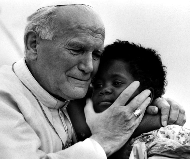 A file photograph of Pope John Paul II hugs three-year-old Monik and her one-year-old sister Zin in Madagascar