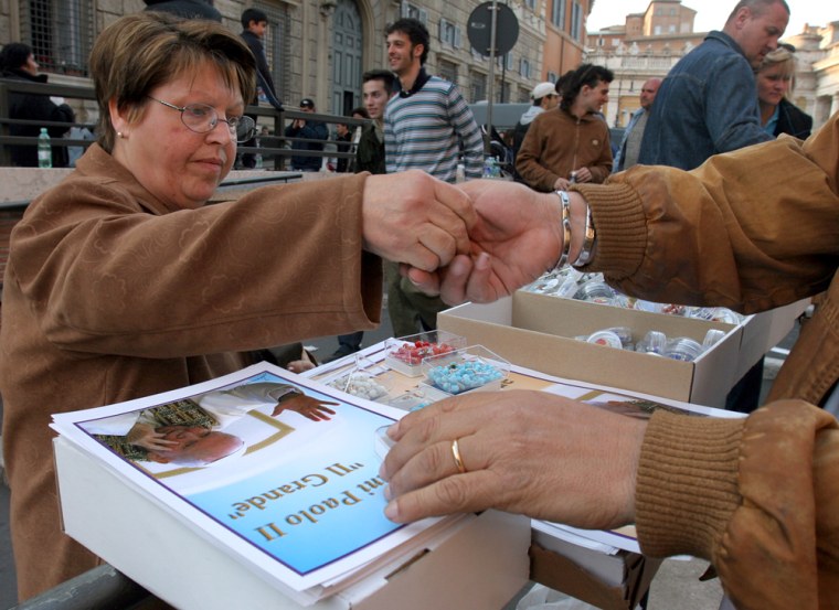 A faithful buys a Pope's souvenir at a stall at the Vatican City, Wednesday. Rome is bracing for an unprecedented flow of pilgrims — some predict their numbers may match the city's own 3 million residents — for the days leading to the pontiff's funeral on Friday.