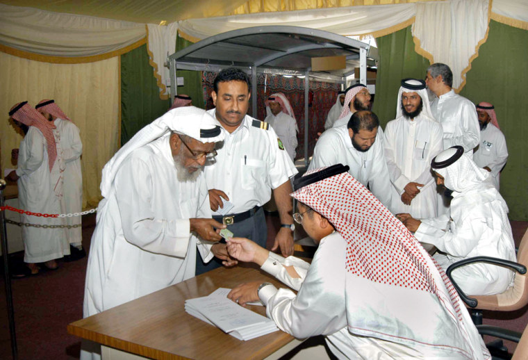 A Saudi official checks papers of elderly voter Abad Al-Magrashy, left, at a voting center in Jiddah on Thursday.