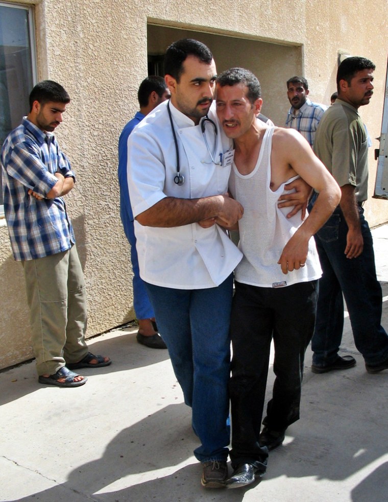 A doctor comforts an injured man at the local hospital in Tikrit on Sunday after two bombs went off outside a nearby police academy.