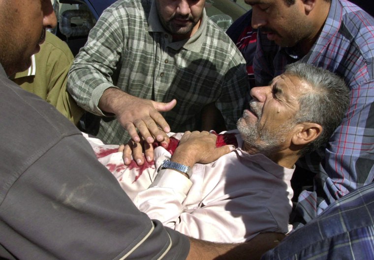 Iraqis help Hameed Shihab, 52, who was wounded when clashes between gunmen and U.S. Army forces erupted at the northern checkpoint in Ramadi, 70 miles west of Baghdad, Iraq, on Tuesday.