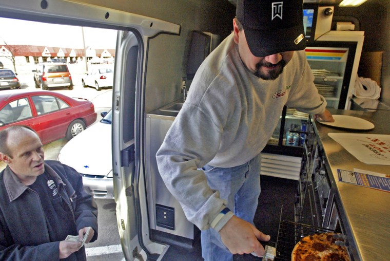 Victor Lozada, right, checks on a pizza that was cooked in the van's mobile kitchen while en route to Edward Conrad in Fond du Lac, Wis. earlier this year. Super Fast Pizzas cooks the pizza while on the road which allows them to dramatically reduce the waiting time for the food.