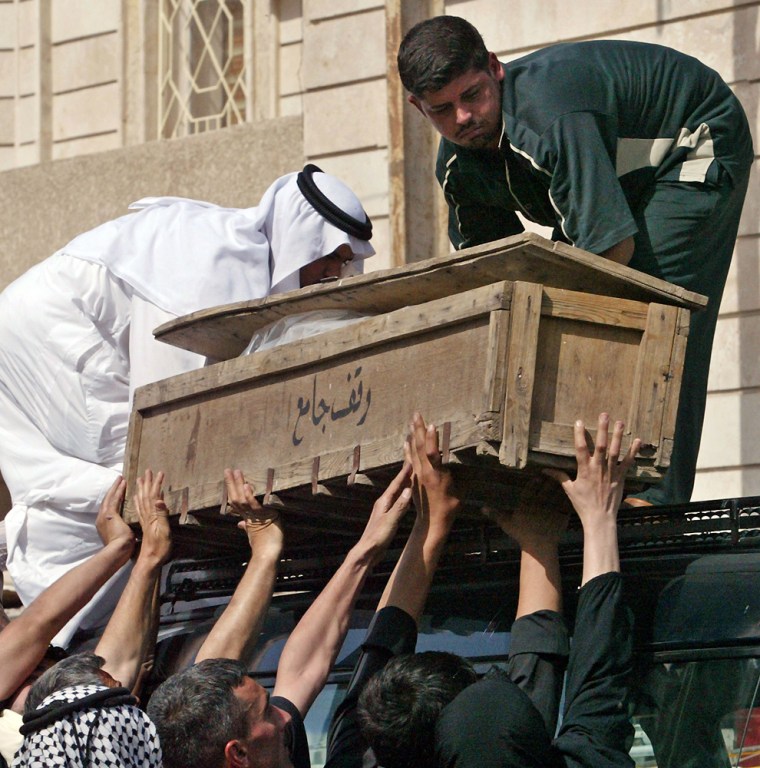 Coffin of slain Iraqi Foreign Ministry official is loaded onto vehicle for funeral in Baghdad