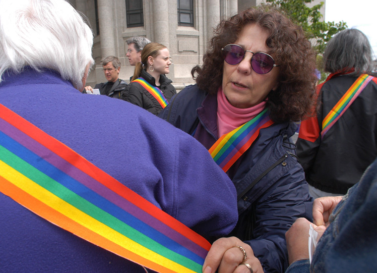 Ivy Dumas, center, adjusts a sash on a Rainbow Sash Alliance supporter outside the St. Paul Cathdral on Sunday.